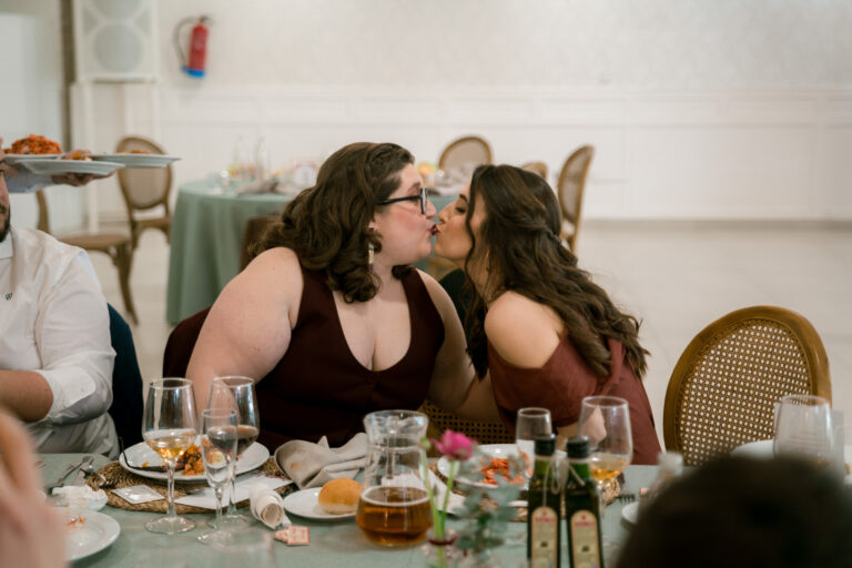 Invitadas dándose un beso en la mesa del banquete de una boda
