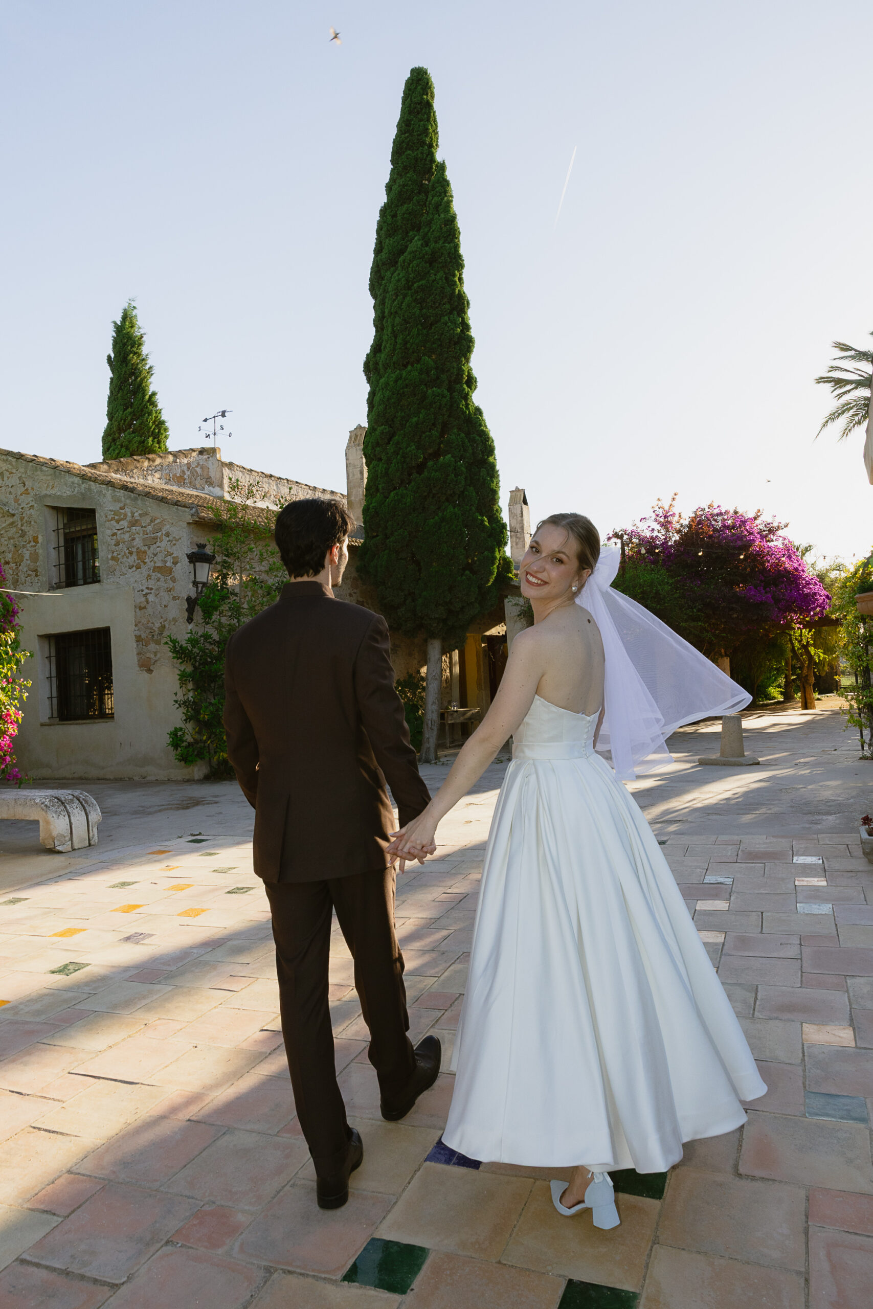 Novios paseando entre cipreses en Finca La Carrasca — boda en la Vega Baja